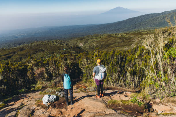 Hikers taking break after the hiking trip on Mount Kilimanjaro while enjoying the beautiful view of blue mountain and the green valley
